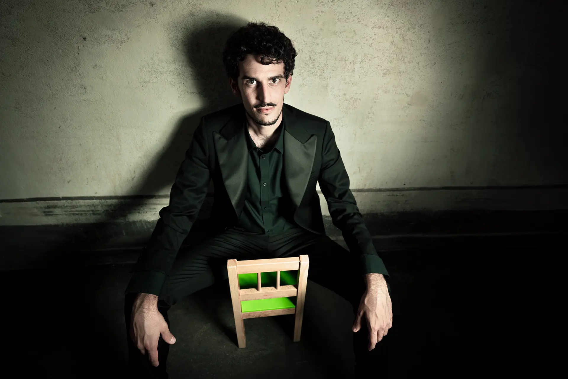 Federico Ercoli in a jacket on a miniature green chair.