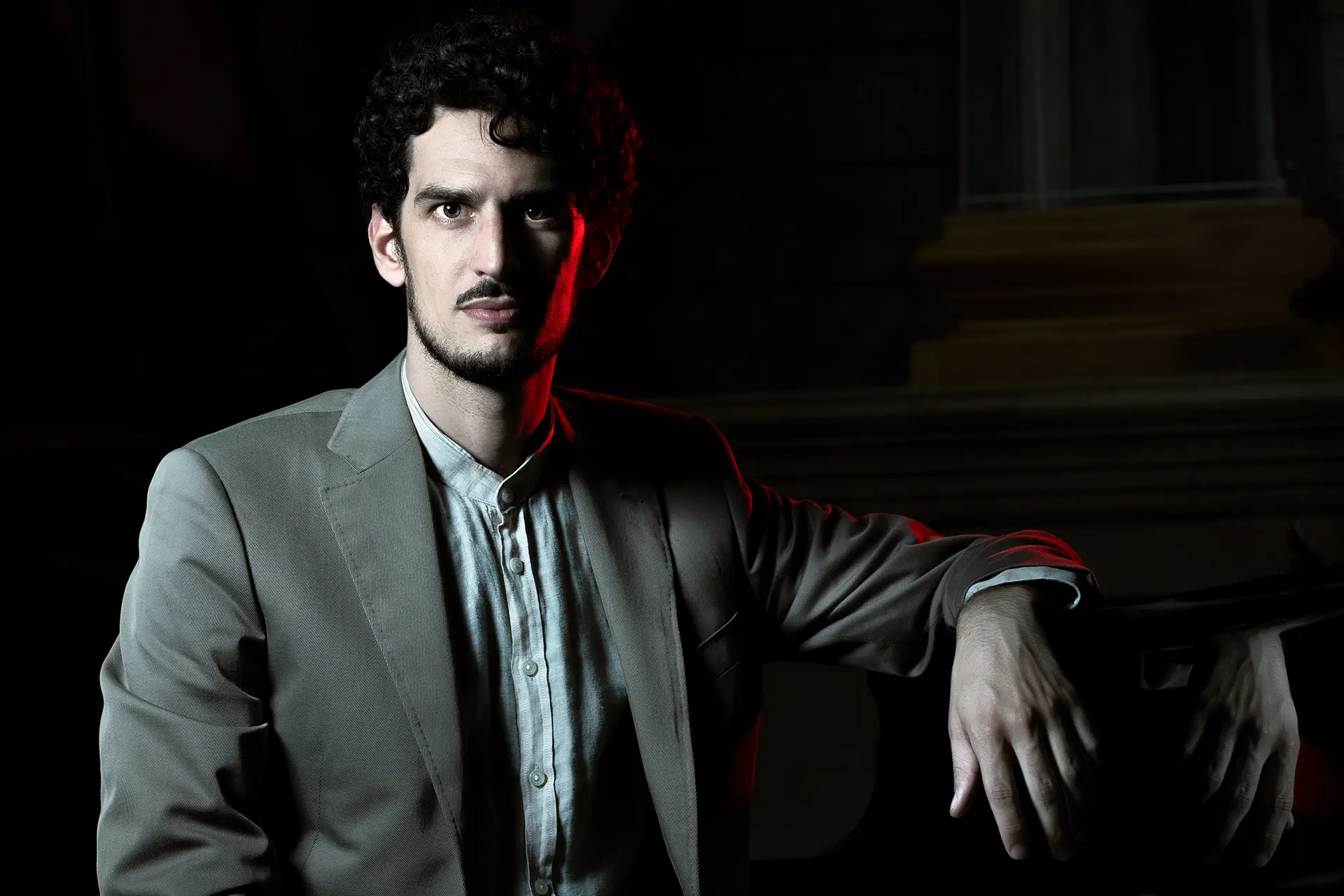 Federico Ercoli in a jacket with a dark background and artistic lighting.