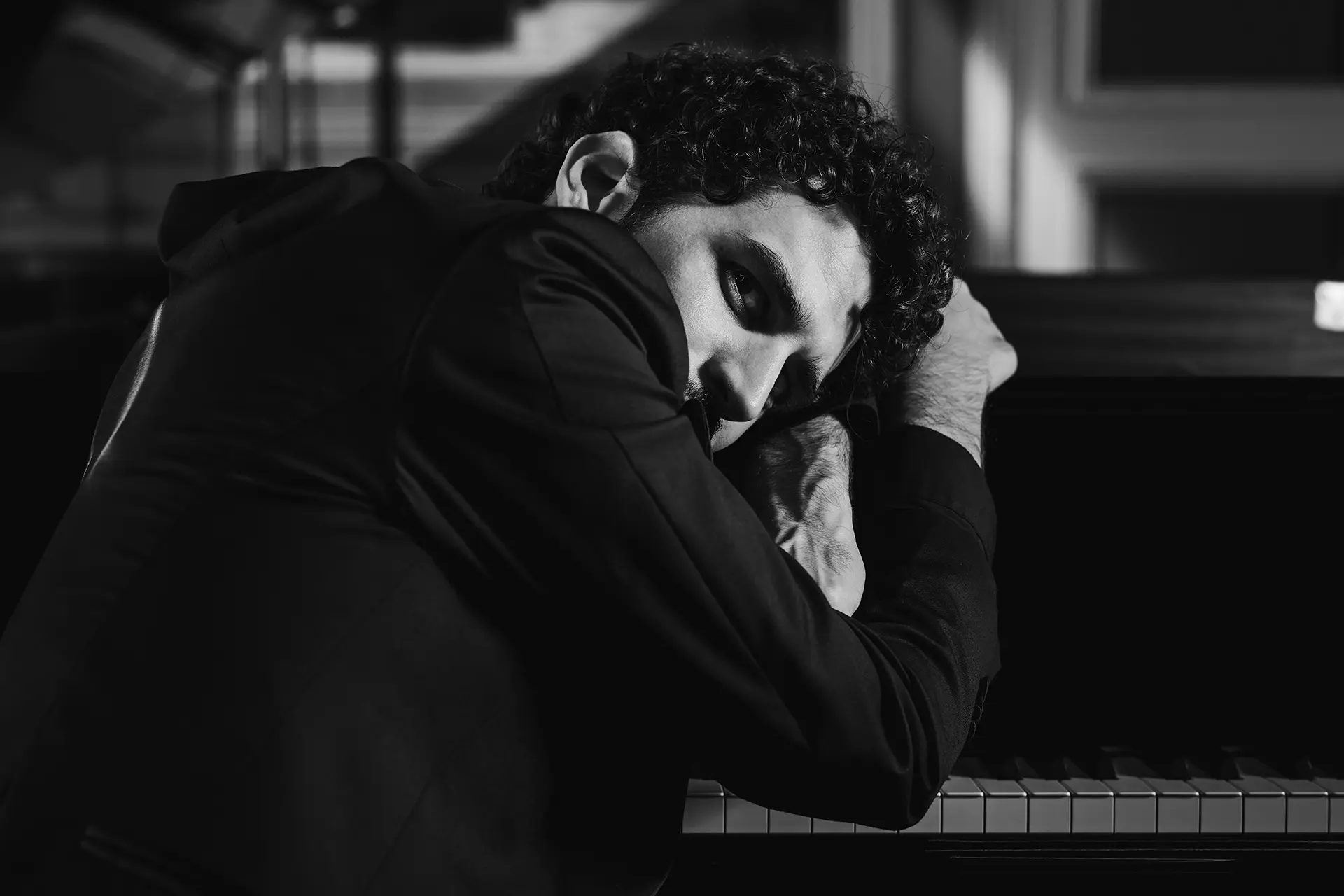 Federico Ercoli leaning on a piano in black and white.