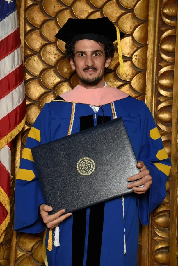 Federico Ercoli wearing a gown and cap at a ceremony.